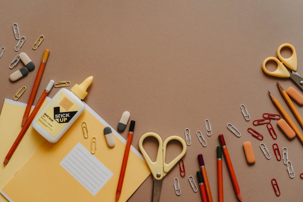 Crafting Captivating Headlines: Your awesome post title goes here Flat lay of assorted stationery items like scissors, pencils, and paper clips on a brown background.