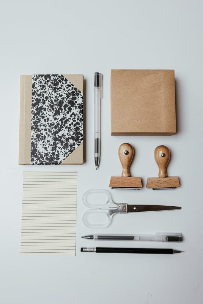 The Art of Drawing Readers In: Your attractive post title goes here Top view of neatly arranged office supplies including notepad, pens, and stamps on white background.